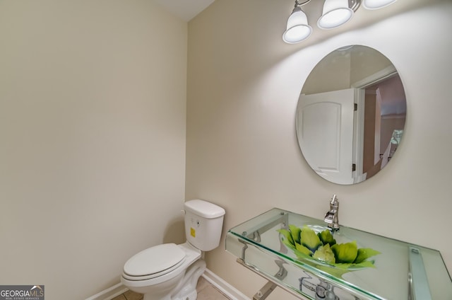 half bathroom featuring toilet, a notable chandelier, tile patterned flooring, and baseboards