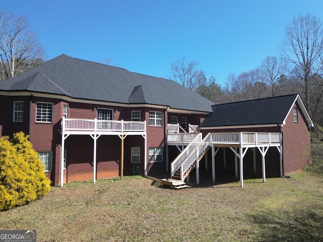 back of house with a lawn, brick siding, stairs, and a deck