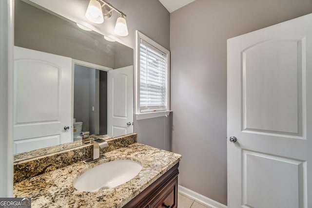 bathroom with baseboards, vanity, tile patterned flooring, and toilet