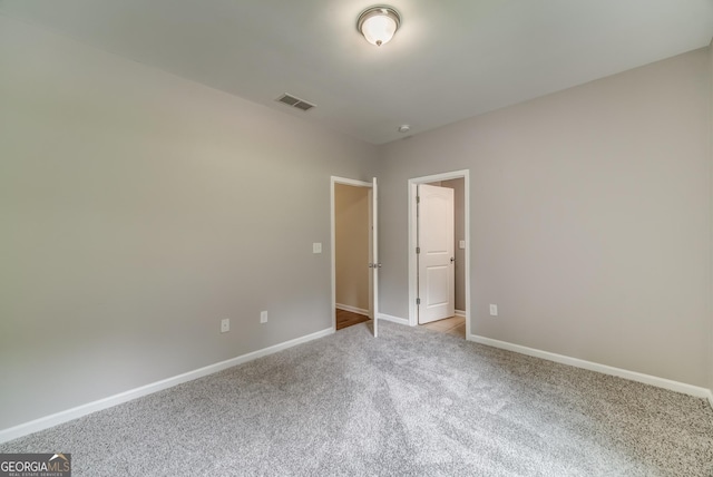 carpeted empty room with visible vents and baseboards