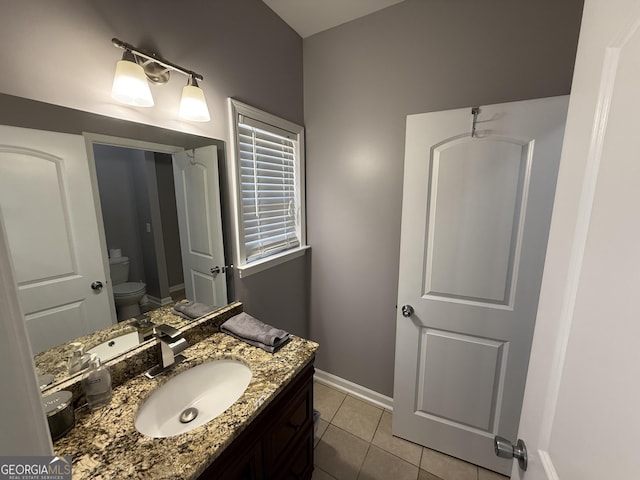bathroom with toilet, vanity, tile patterned floors, and baseboards