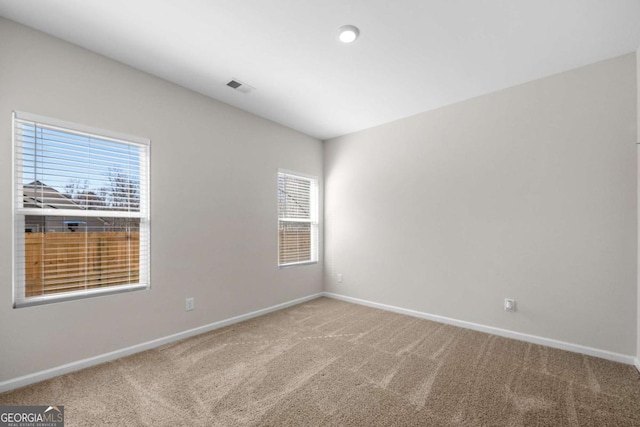 spare room featuring carpet flooring, baseboards, and visible vents