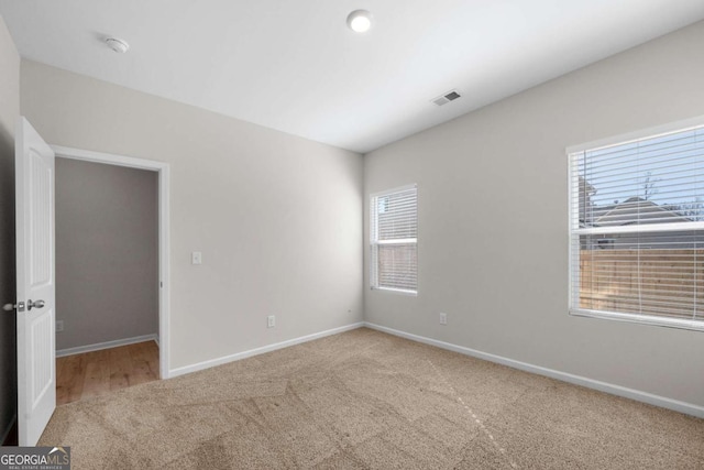 spare room with visible vents, baseboards, and carpet flooring