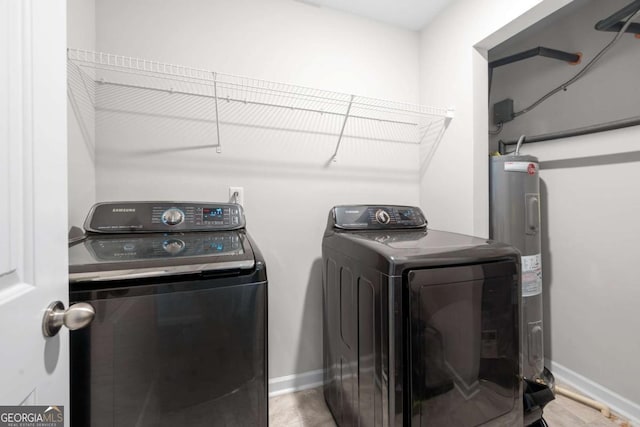 clothes washing area with water heater, baseboards, washer and dryer, and laundry area