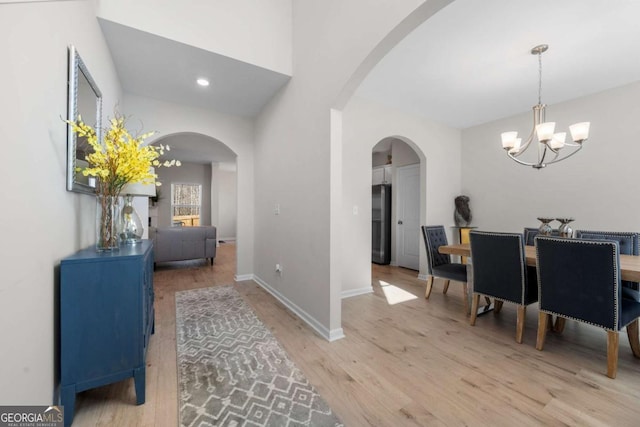 foyer featuring a notable chandelier, baseboards, recessed lighting, light wood-style floors, and arched walkways