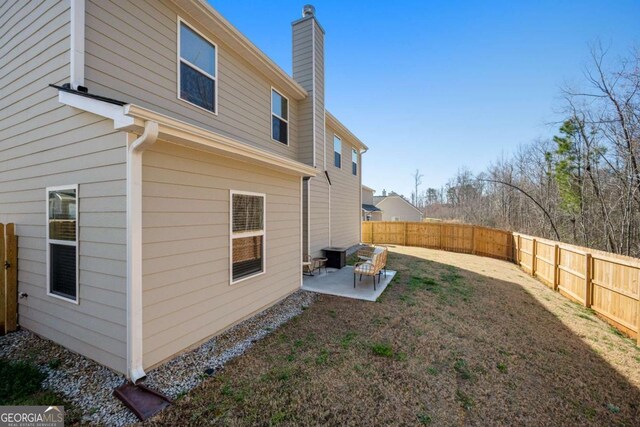 exterior space featuring a yard, a fenced backyard, a patio, and a chimney