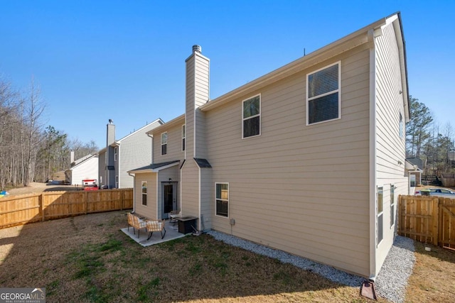 rear view of property with a patio, a fenced backyard, and a chimney