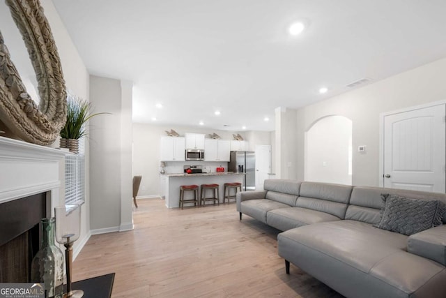 living area with recessed lighting, visible vents, a fireplace with flush hearth, and light wood-style flooring