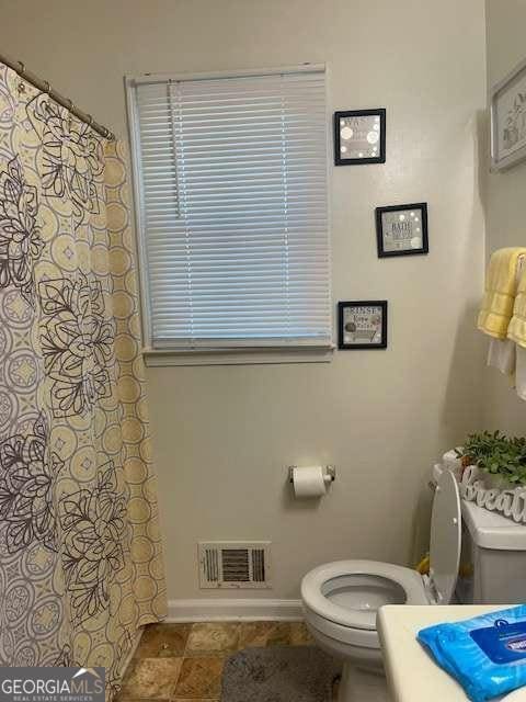 bathroom with a shower with shower curtain, visible vents, baseboards, and toilet