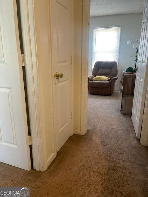 hall with light carpet and a textured ceiling