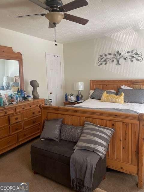 bedroom featuring a ceiling fan, light colored carpet, and a textured ceiling