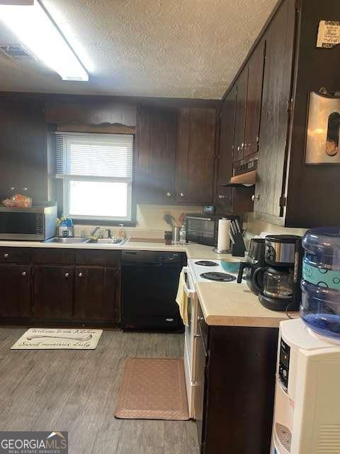 kitchen featuring light wood finished floors, a sink, light countertops, dishwasher, and stainless steel microwave