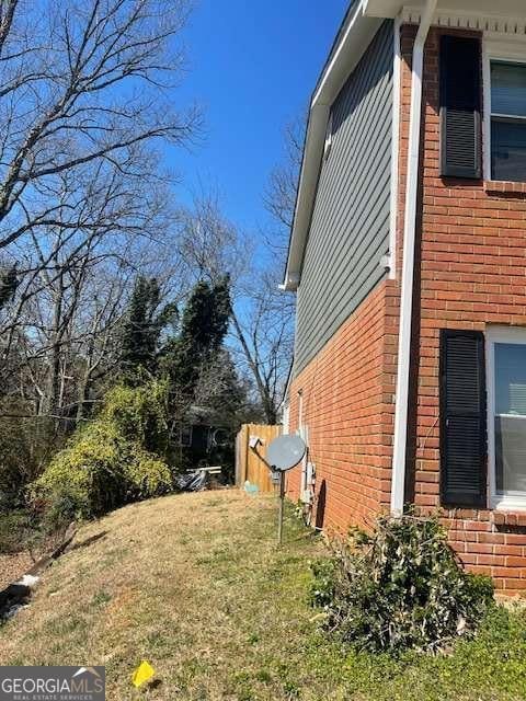 view of side of property with brick siding and fence