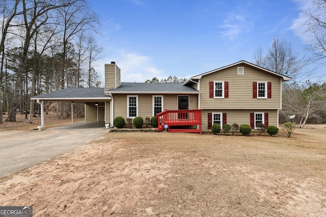 tri-level home with a carport, roof with shingles, driveway, and a chimney