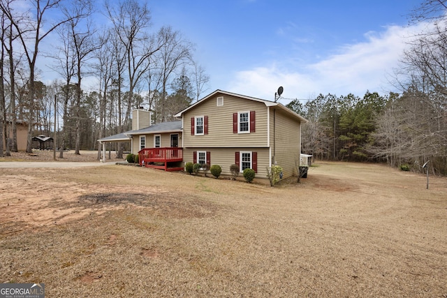 view of front of house featuring a wooden deck, driveway, and a chimney