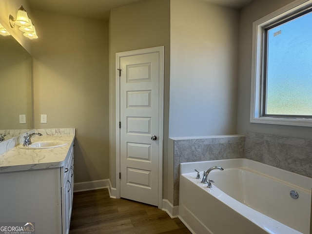 full bath featuring baseboards, wood finished floors, a bath, and vanity