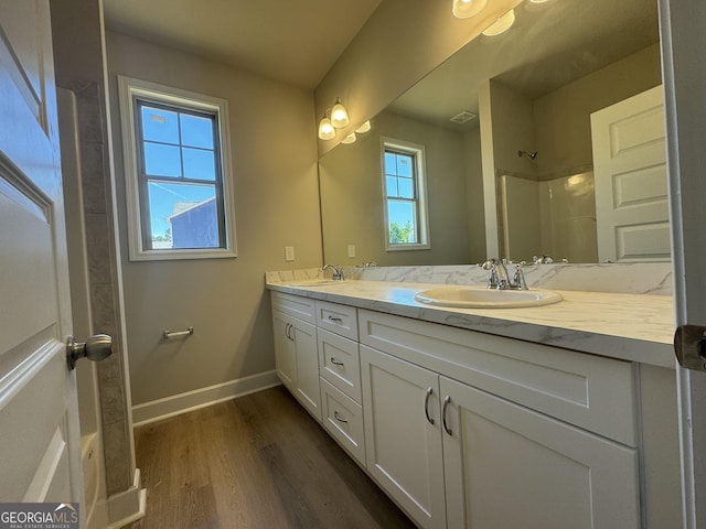 full bathroom featuring double vanity, wood finished floors, baseboards, and a sink