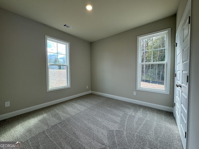 carpeted spare room featuring visible vents, plenty of natural light, and baseboards