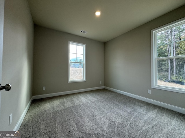 carpeted empty room featuring visible vents, plenty of natural light, and baseboards