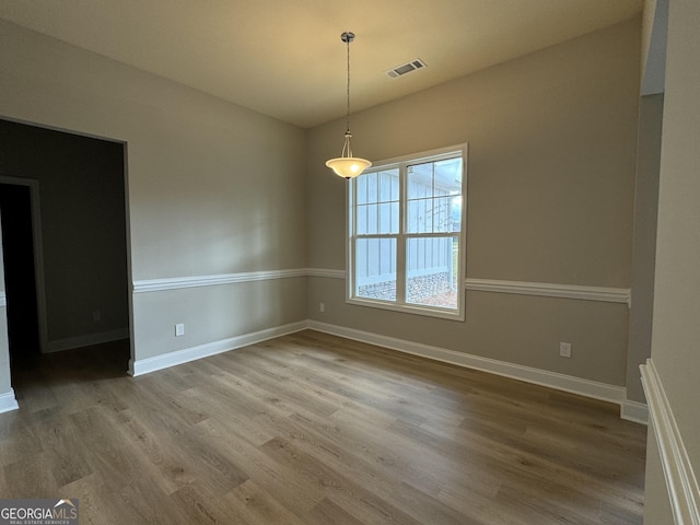 unfurnished dining area with visible vents, baseboards, and wood finished floors