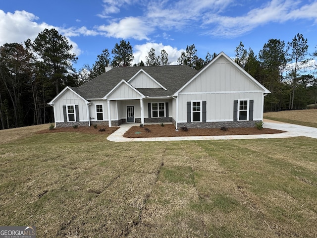 modern farmhouse style home with stone siding, board and batten siding, a shingled roof, and a front yard