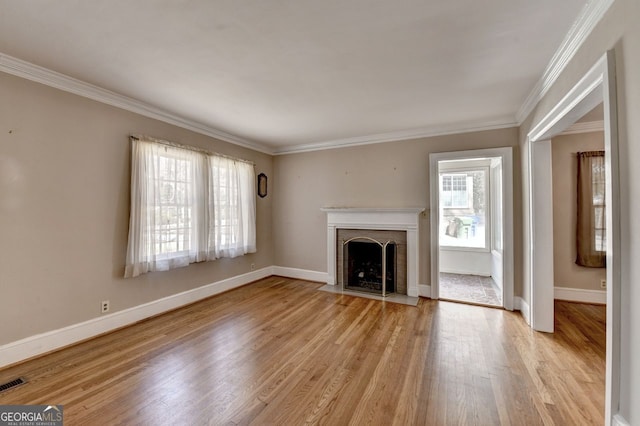 unfurnished living room with baseboards, visible vents, a fireplace with flush hearth, light wood-style floors, and crown molding