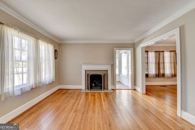 unfurnished living room with a wealth of natural light, crown molding, and light wood-type flooring