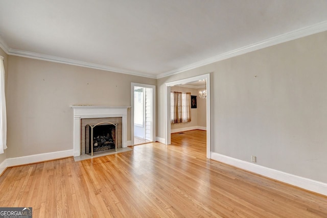 unfurnished living room featuring baseboards, ornamental molding, a fireplace with flush hearth, and light wood finished floors