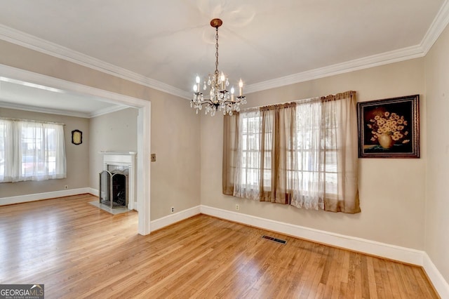 interior space with wood finished floors, visible vents, baseboards, a fireplace, and crown molding