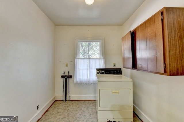 washroom featuring baseboards, cabinet space, and washer / dryer