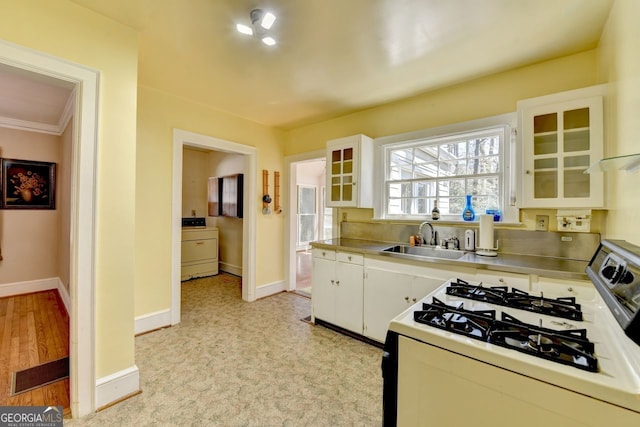 kitchen with a sink, washer / clothes dryer, white cabinets, and white gas range oven