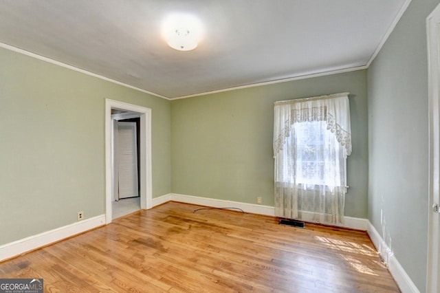 spare room featuring visible vents, wood finished floors, baseboards, and ornamental molding