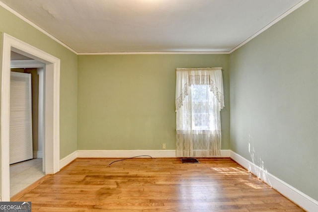 spare room featuring crown molding, wood finished floors, visible vents, and baseboards