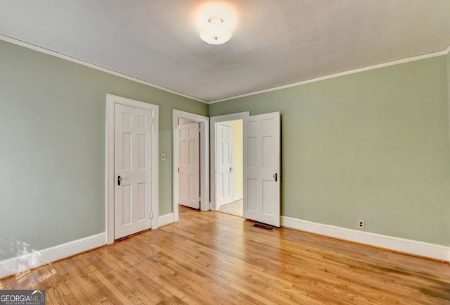 unfurnished bedroom with light wood finished floors, visible vents, crown molding, and baseboards