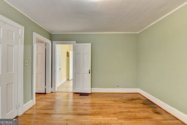 unfurnished bedroom with baseboards, crown molding, and light wood finished floors