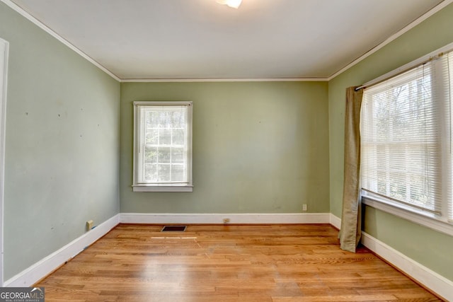 empty room featuring light wood finished floors, visible vents, and plenty of natural light