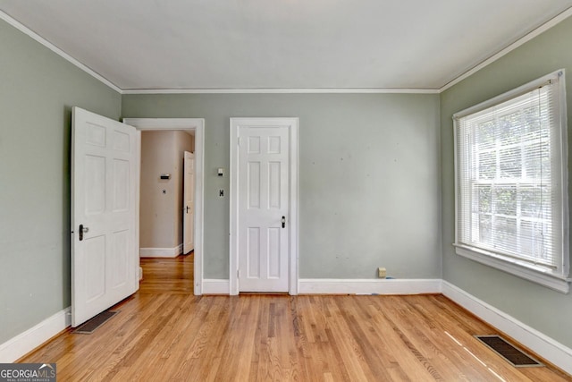 unfurnished bedroom featuring visible vents, light wood-style flooring, and crown molding