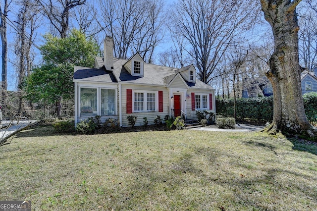 new england style home featuring a chimney and a front yard