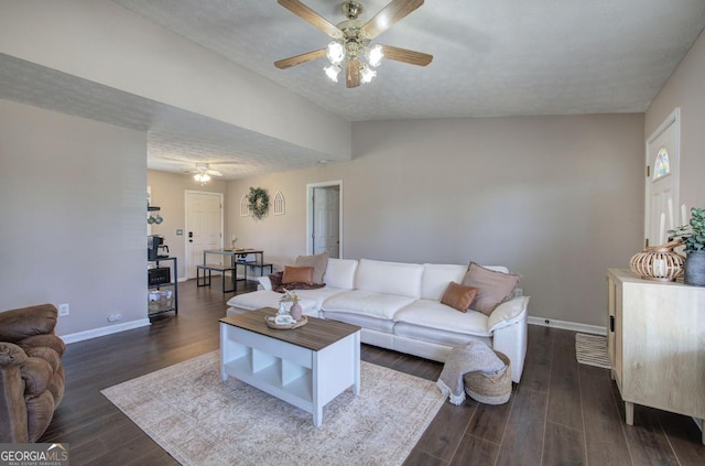 living area with ceiling fan, a textured ceiling, baseboards, and dark wood-style flooring