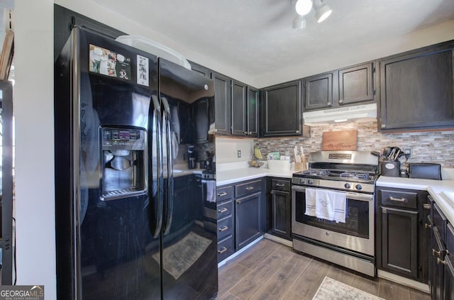 kitchen featuring stainless steel gas range oven, under cabinet range hood, black refrigerator with ice dispenser, and light countertops