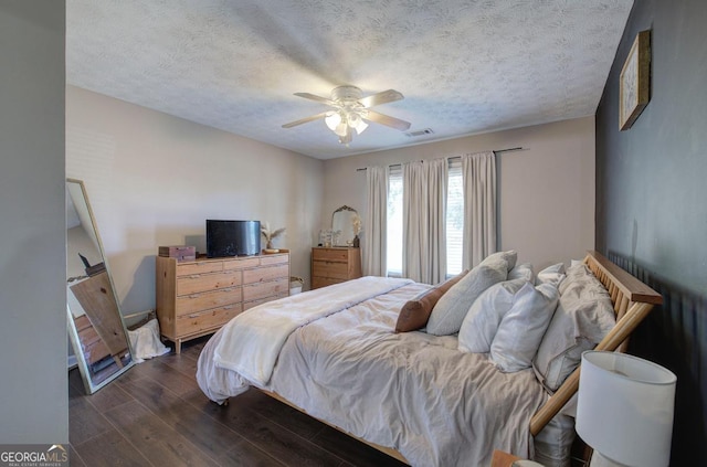 bedroom featuring dark wood finished floors, ceiling fan, visible vents, and a textured ceiling