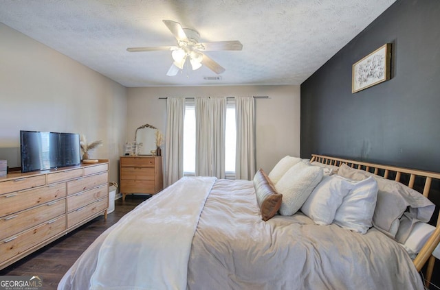 bedroom featuring visible vents, a textured ceiling, ceiling fan, and dark wood-style flooring