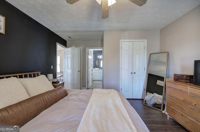 bedroom featuring dark wood-type flooring, ensuite bathroom, a closet, a textured ceiling, and a ceiling fan