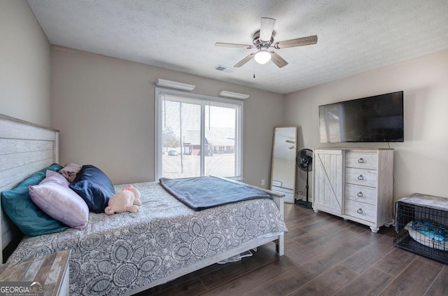 bedroom featuring dark wood finished floors, a ceiling fan, visible vents, and a textured ceiling