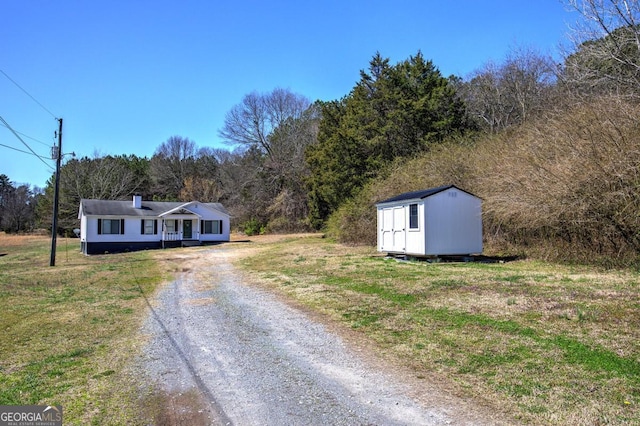 view of front of home featuring an outbuilding, a storage unit, and driveway