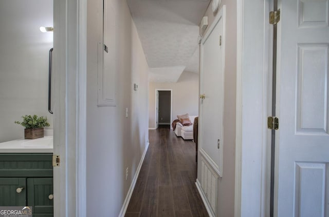 hallway with visible vents, baseboards, and dark wood-type flooring