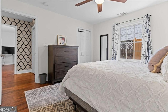 bedroom with visible vents, ceiling fan, baseboards, wood finished floors, and a closet