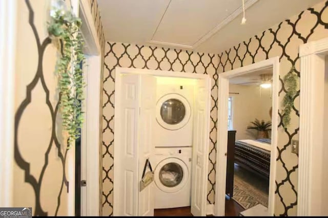 laundry area with wallpapered walls, attic access, laundry area, and stacked washer / dryer