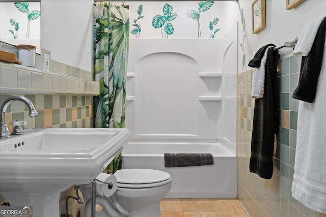 full bath featuring tile patterned floors, toilet, shower / bath combo with shower curtain, and a sink