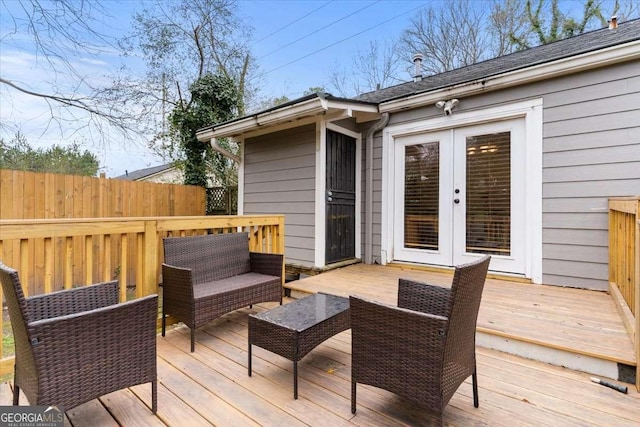 wooden terrace with outdoor lounge area, french doors, and fence